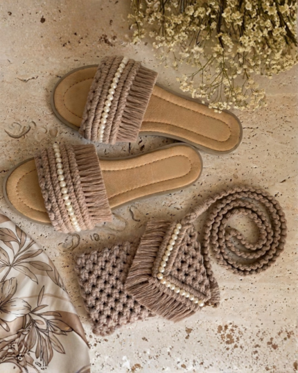 Embrace understated luxury with our 2-Piece Handcrafted Pearl-Embellished Macrame Set, featured on Sharqiyat Online. This exquisite collection features a coordinated micro-crossbody phone bag and matching slide sandals, beautifully hand-knotted in a rich, warm taupe cotton cord. Highlighted by a delicate line of pristine faux pearls and finished with a soft, dense fringe, this set effortlessly blends bohemian charm with a touch of classic elegance.