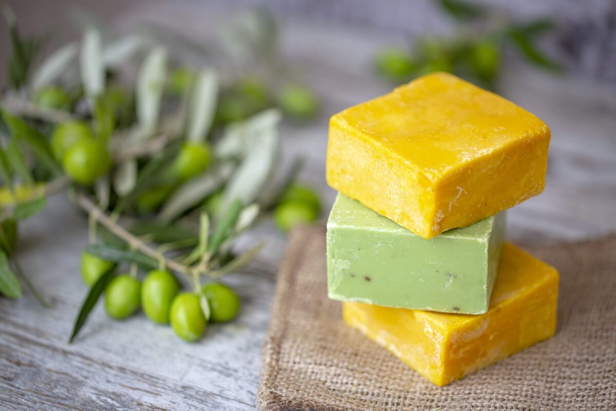 Stack of three olive-oil soap bars on burlap with olive branches